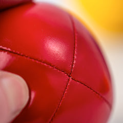 Close-up of a red leather ball with a blurred yellow and white background