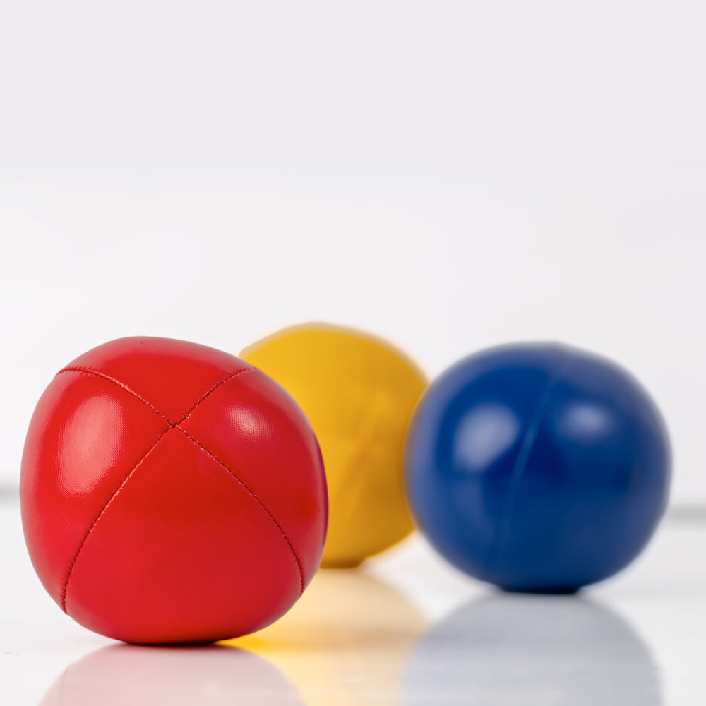 Three colorful balls (red, yellow, blue) on a reflective surface with a white background