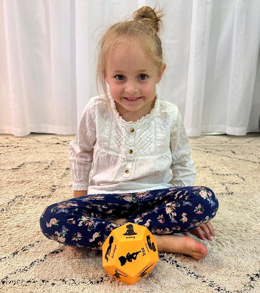 Little girl doing yoga pose with kids yoga dice